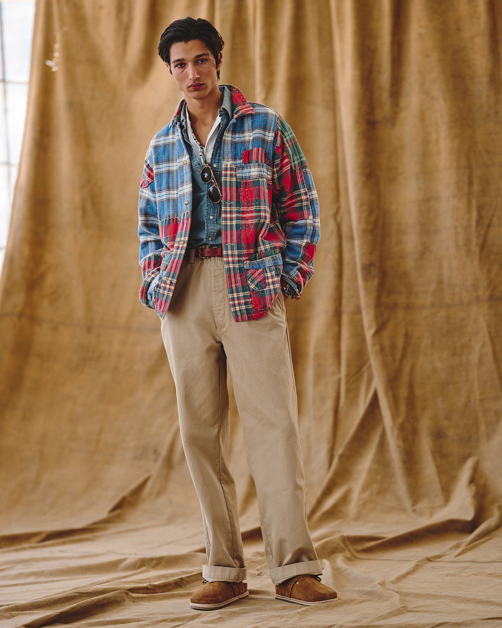 Ein Mann trägt ein Flanellhemd über einem Denimhemd, dazu beige Hosen und Loafers.