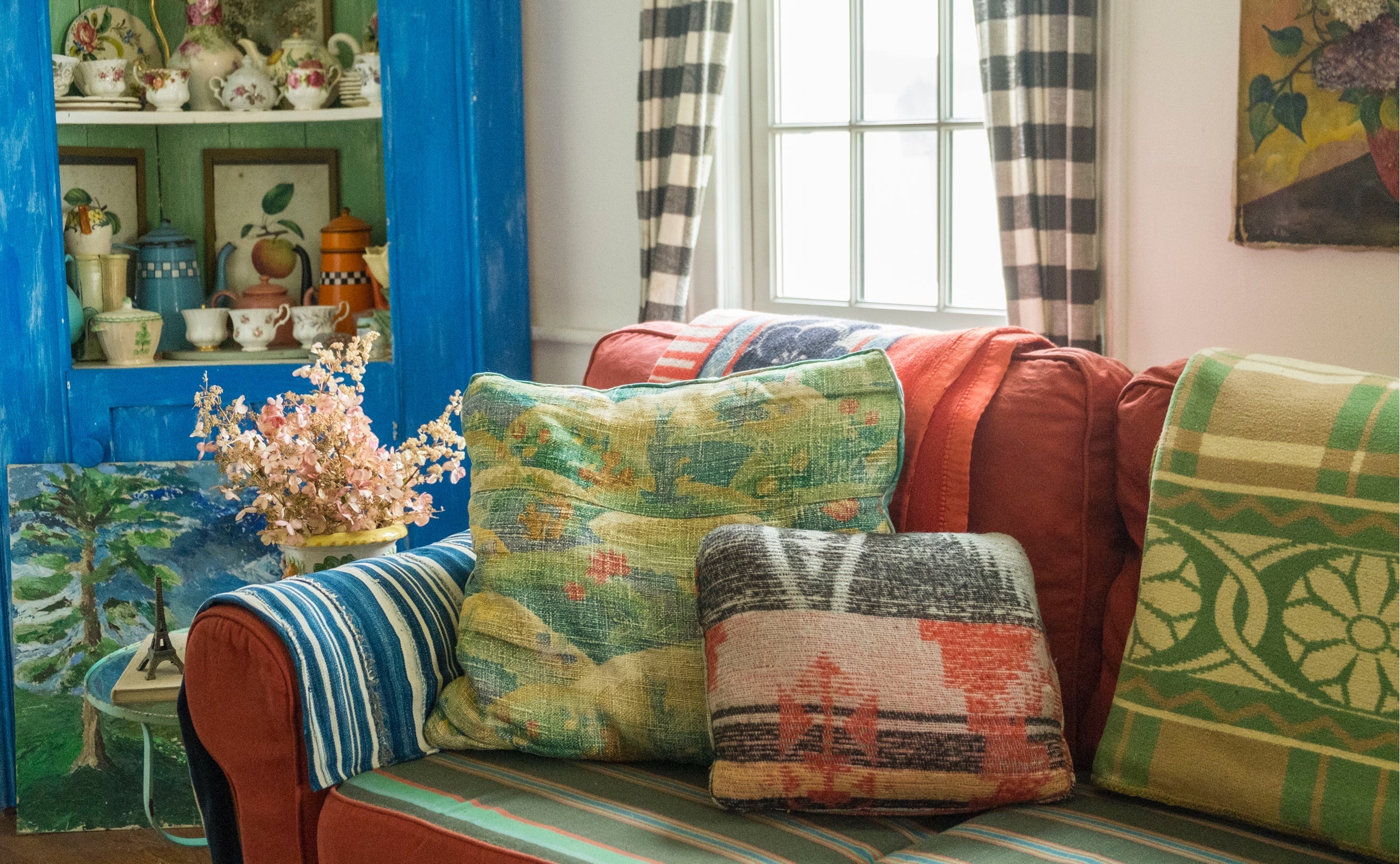 Ein neues Sofa bekommt sofort Charakter: mit vintage Decken, Textilien und einem bunten Mix an Kissen. Das blaue Regal beherbergt eine Sammlung englischer Teetassen und alter franz&ouml;sischer Kaffeebecher