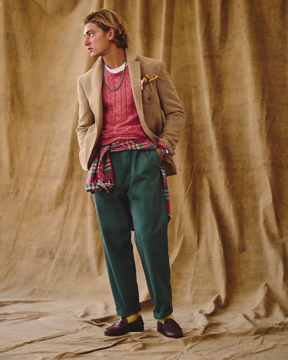 Man in a red jumper, beige blazer, jeans and loafers.