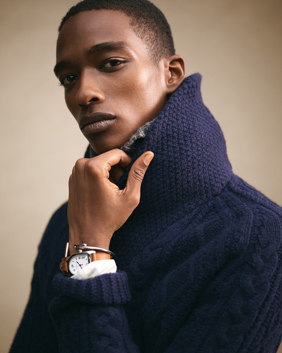 Close up of a man wearing a dark navy cable knit jumper with a high collar.